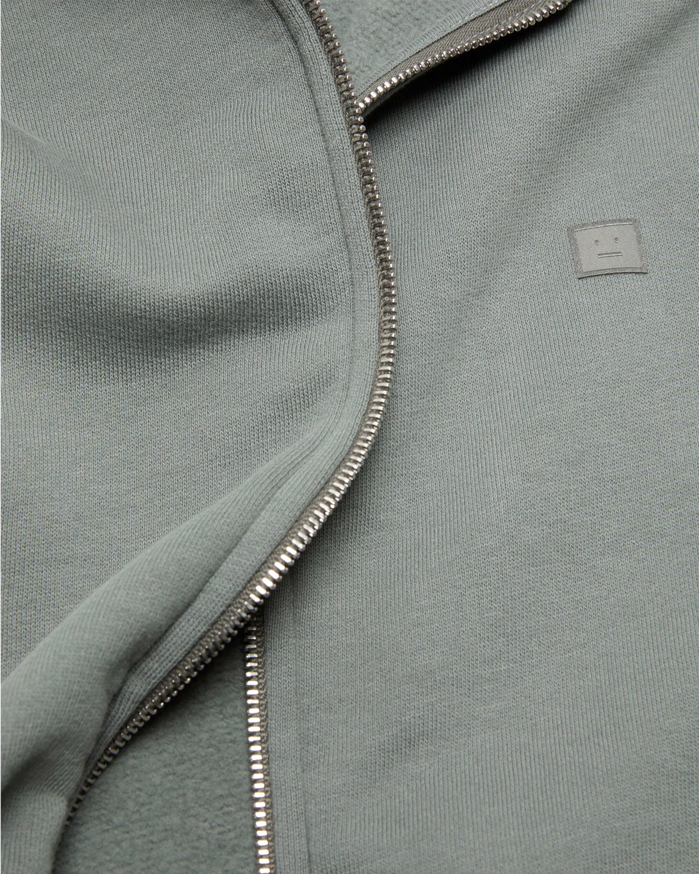 Détail zip et patch logo Sweat à capuche Acne Studios gris pierre face
