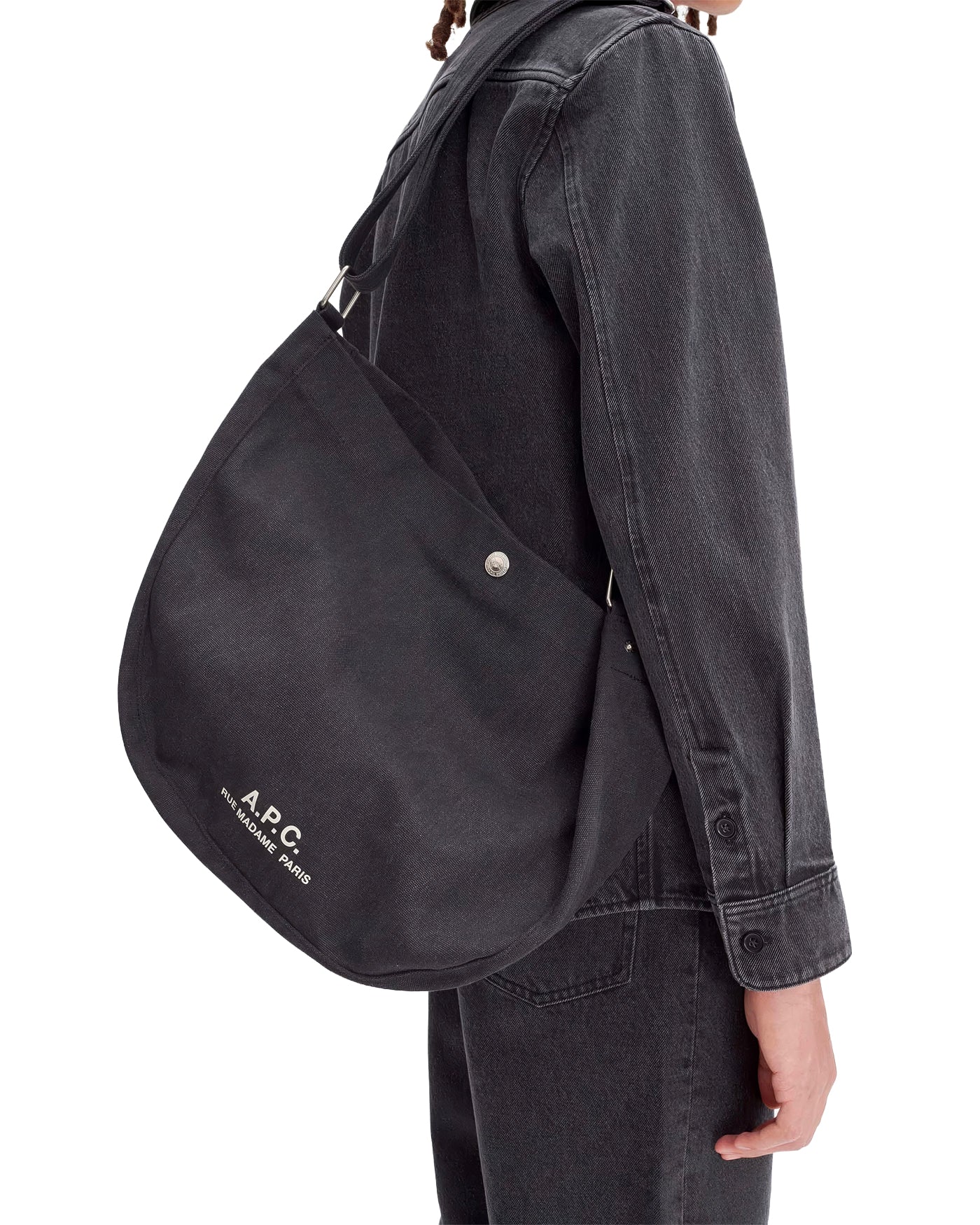 Sac besace Journal A.P.C. noir porté en bandoulière, profil gauche
