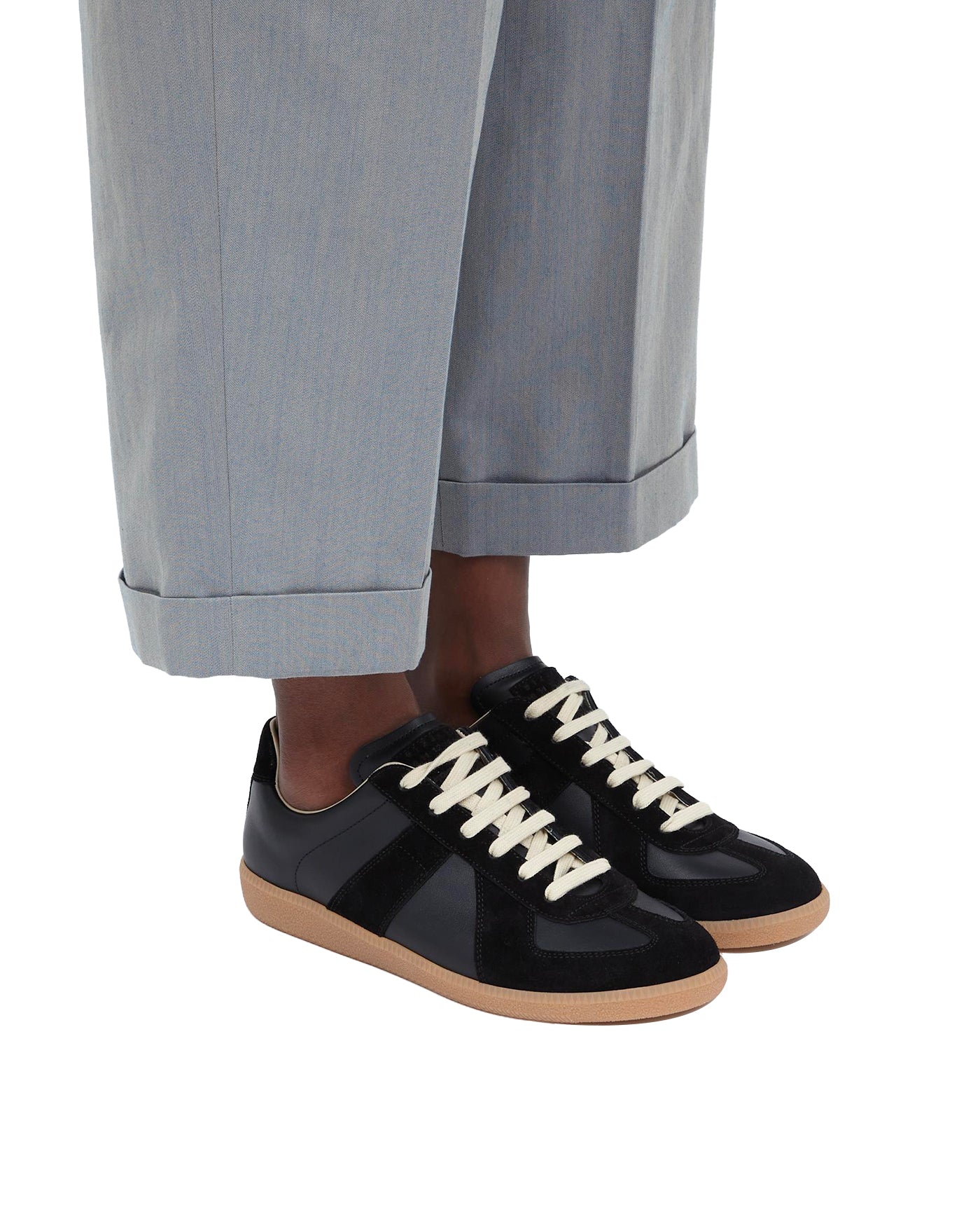 Sneakers Replica Maison Margiela noir portées avec pantalon gris profil gauche
